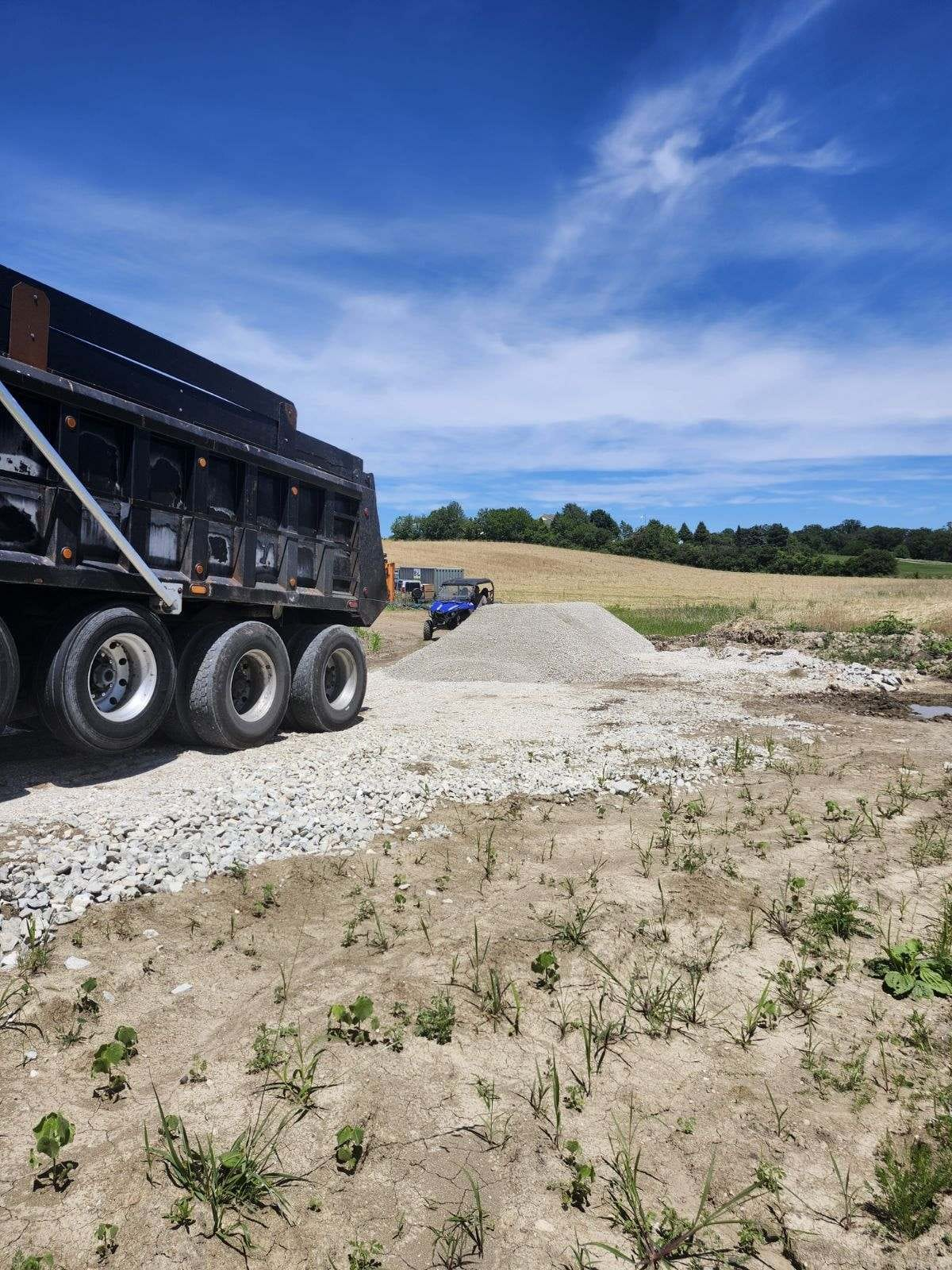 Quad-axle dump truck delivering material