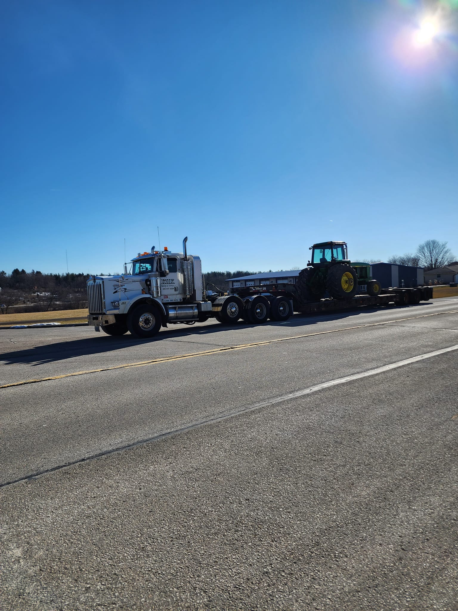 John Deere tractor being hauled on a lowboy trailer